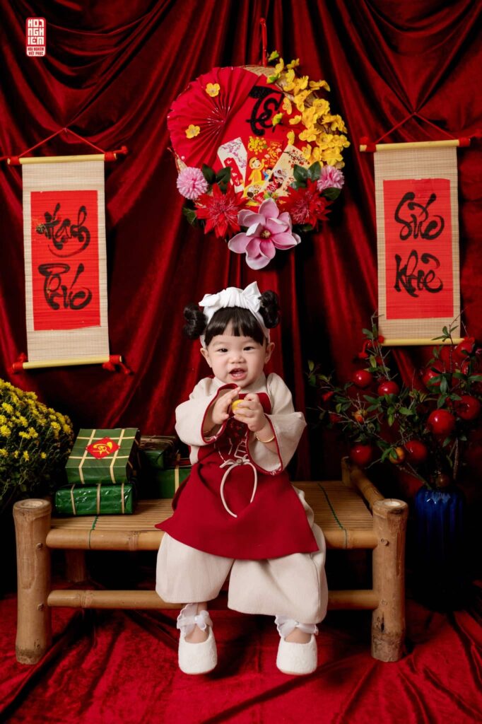 Bé gái mặc Việt phục truyền thống màu đỏ chụp ảnh Tết tại Hoa Nghiêm Việt Phục Huế
