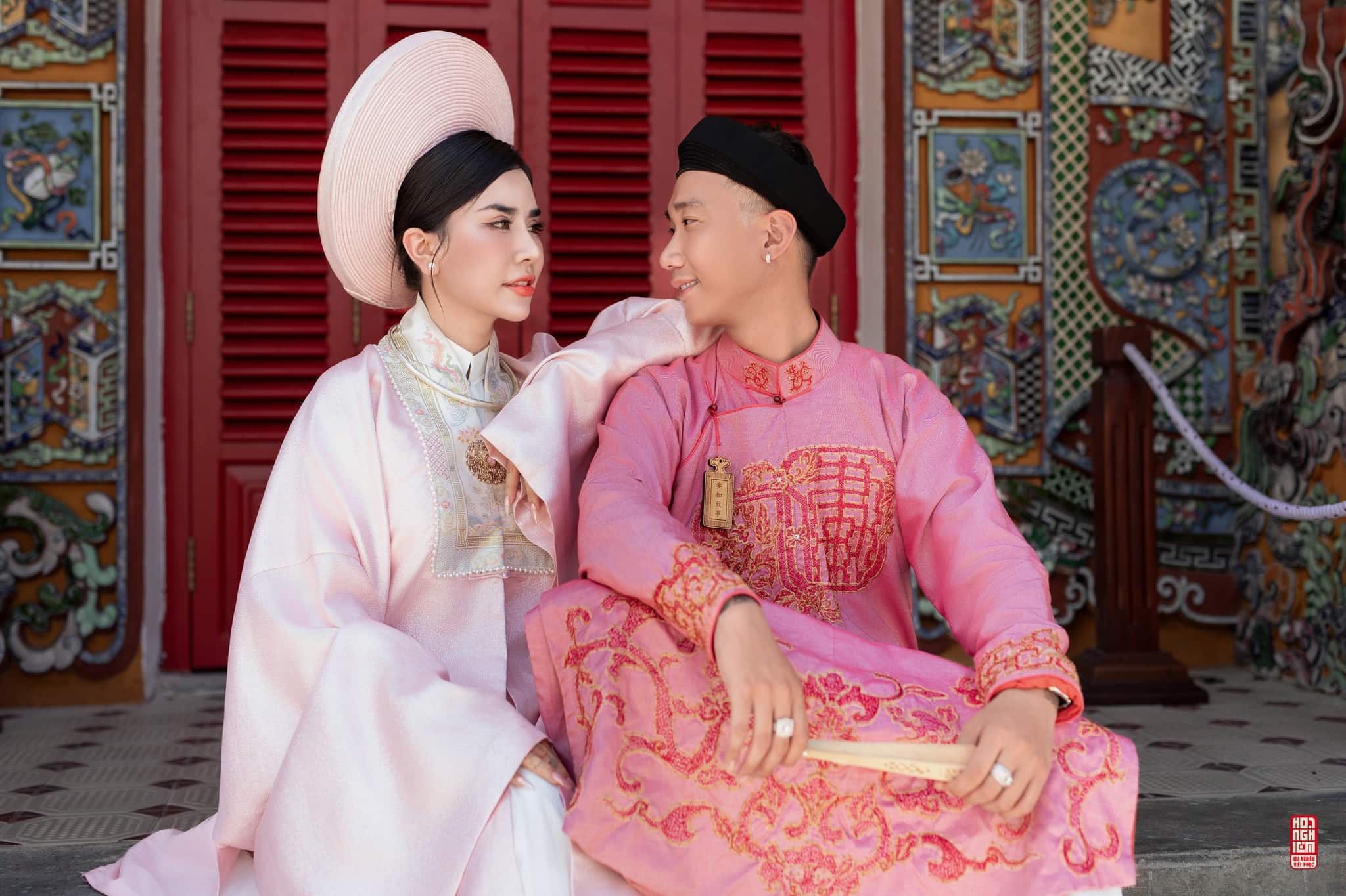 Cổ phục cưới Ngũ Thân – Nhật Bình | Hồng Duyên Cát Lễ Cặp đôi trong cổ phục cưới Ngũ Thân – Nhật Bình ngồi bên nhau trước điện cổ Huế
