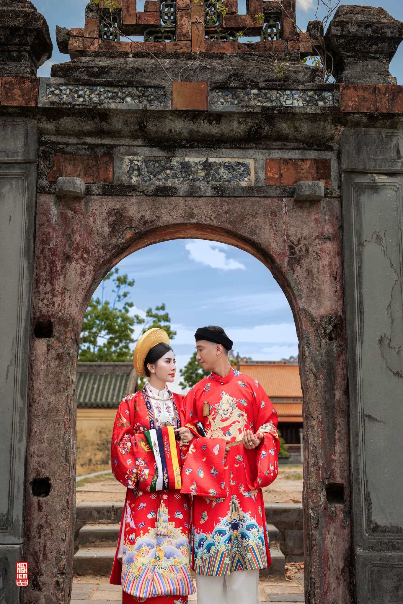 Cổ phục cưới áo Tấc – Nhật Bình trong không gian kiến trúc cổ Cặp đôi mặc cổ phục cưới áo Tấc – Nhật Bình Long Phụng Cát Tường dưới cổng kiến trúc cổ
