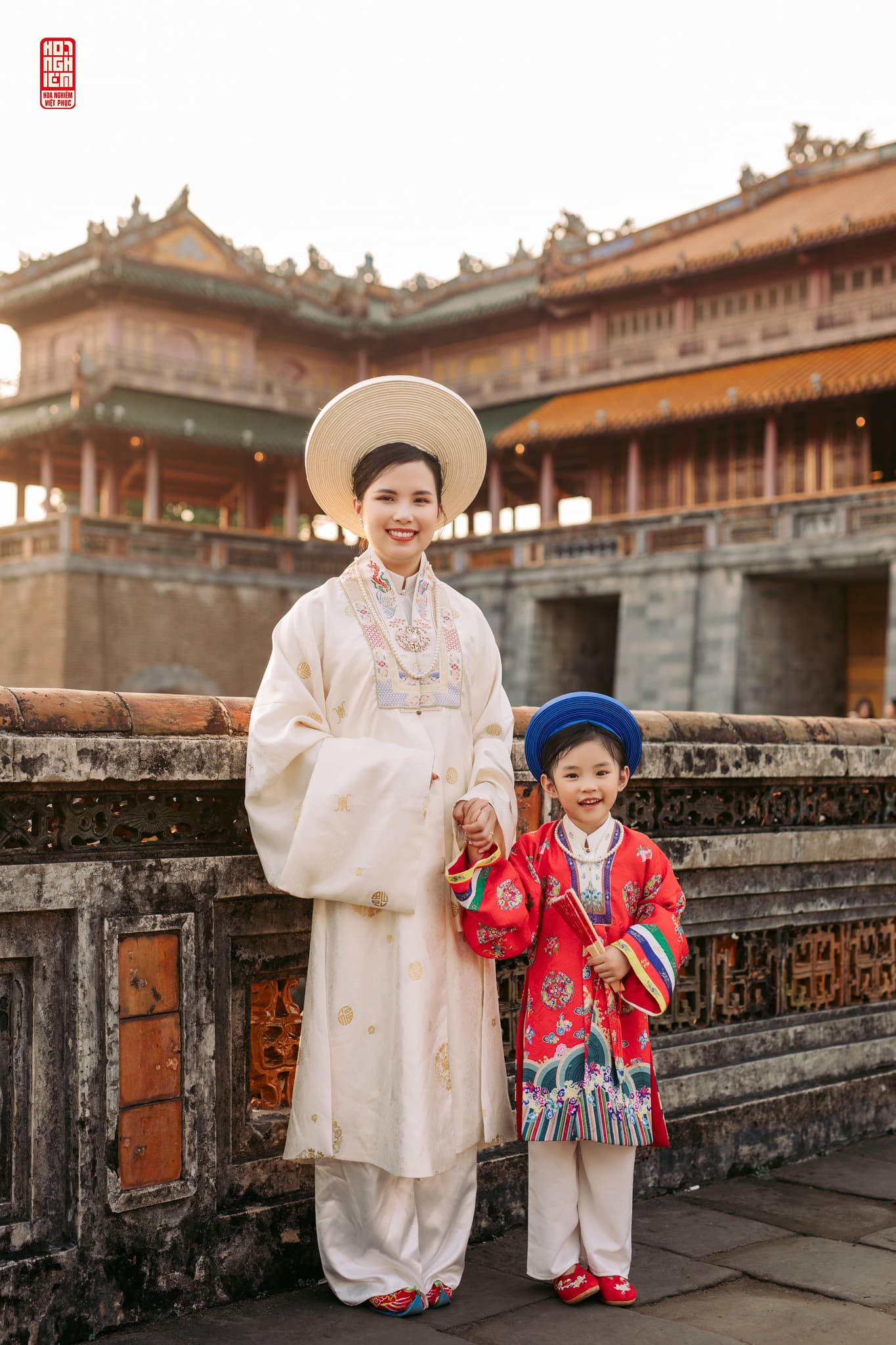 Mẹ và bé gái mặc áo Nhật Bình truyền thống đứng trước kiến trúc cung đình Huế