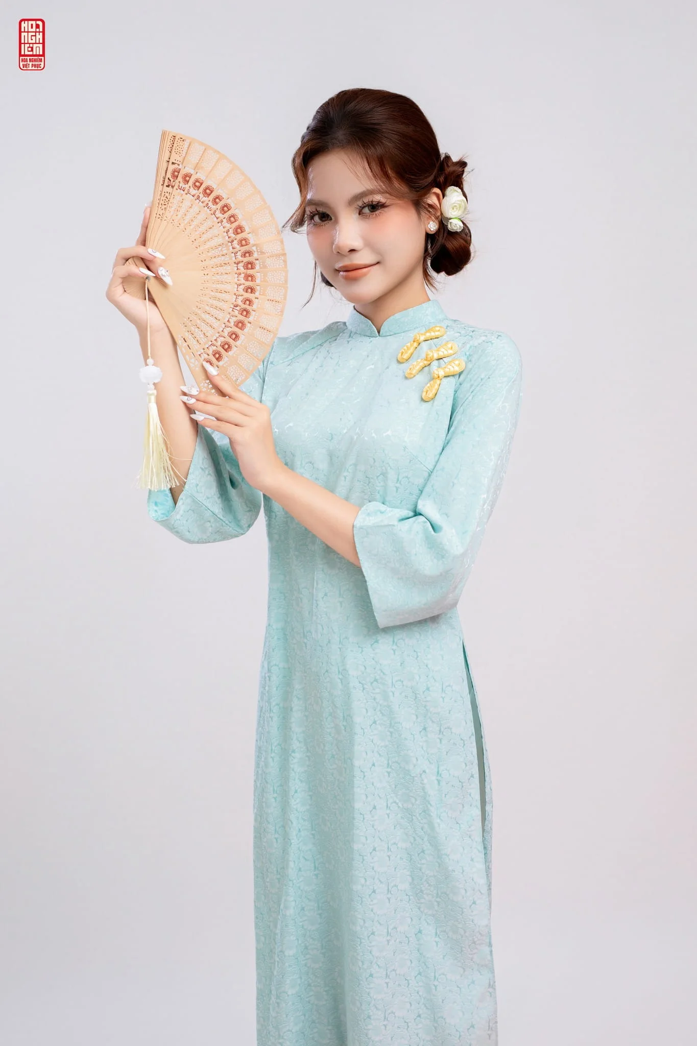 Áo dài suông lụa jacquard đính khuy cách điệu màu xanh ngọc nhạt với chi tiết khuy vai nổi bật mang vẻ đẹp hiện đại và thanh lịch.