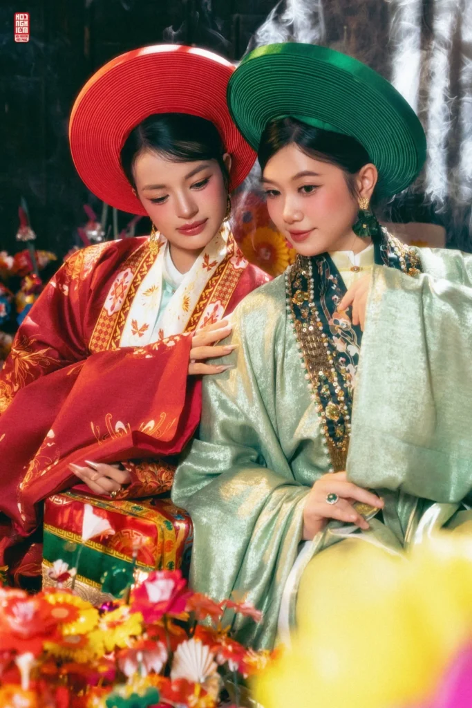 Hai thiếu nữ mặc áo Nhật Bình đỏ và xanh chụp ảnh cổ phong tại làng hoa giấy Thanh Tiên Huế với khung cảnh hoa giấy rực rỡ.