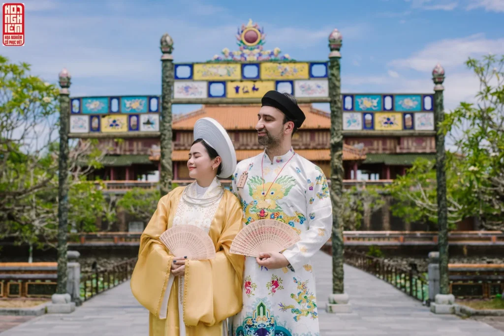 International visitors wearing Vietnamese royal traditional costumes at Hue Imperial Citadel, experiencing cultural photography and costume rental services at Hue heritage sites.