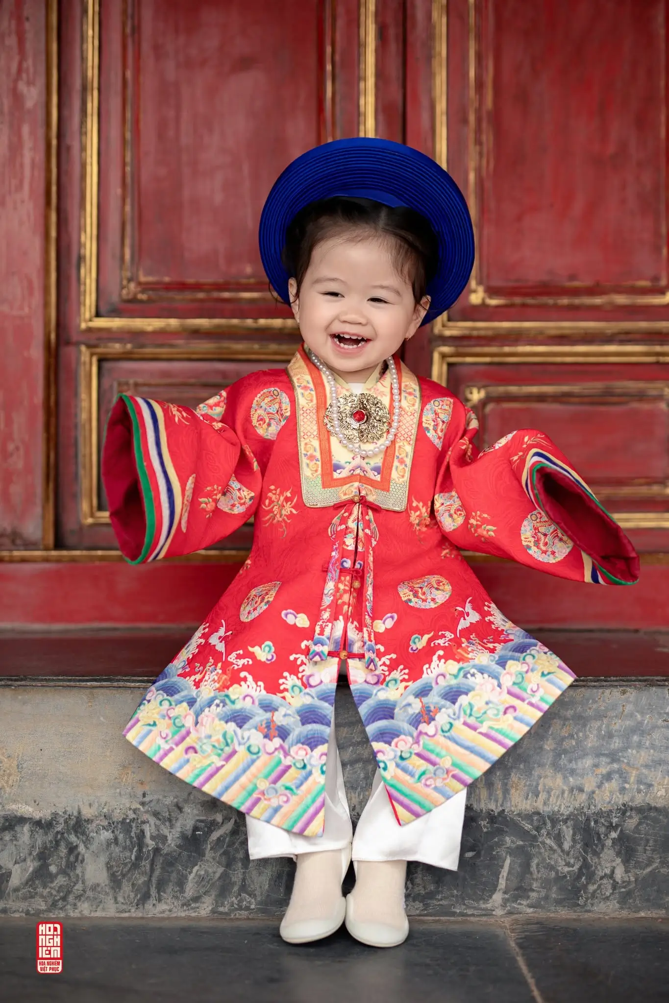Bé gái 2 tuổi mặc Nhật Bình mini cười rạng rỡ Bé gái diện Nhật Bình mini trong bộ Việt phục gia đình ba mẹ và bé gái 2 tuổi, phù hợp chụp ảnh thôi nôi, sinh nhật và lưu giữ tuổi thơ theo phong cách cổ phục.